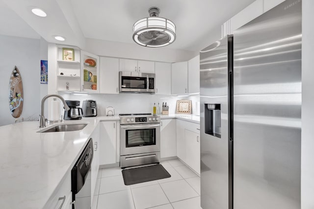 kitchen with light stone countertops, stainless steel appliances, white cabinetry, and sink