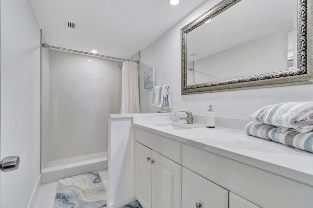 bathroom with tile patterned flooring, vanity, and walk in shower