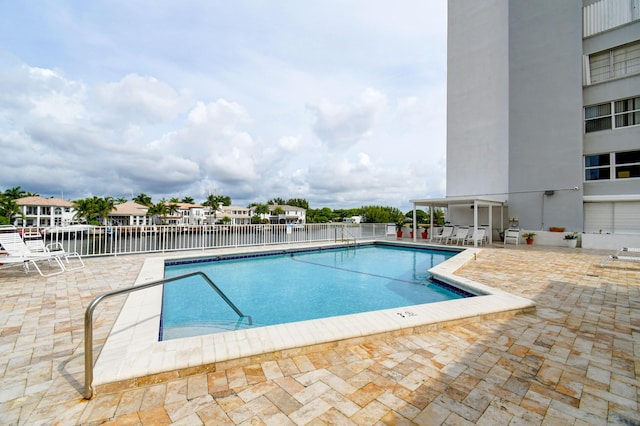 view of swimming pool with a water view and a patio area