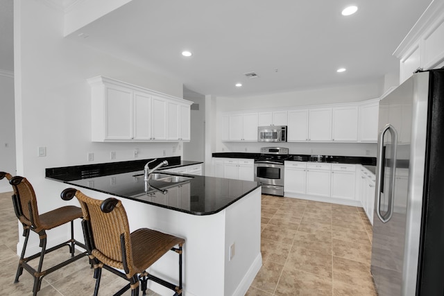 kitchen with a kitchen bar, kitchen peninsula, white cabinets, and appliances with stainless steel finishes