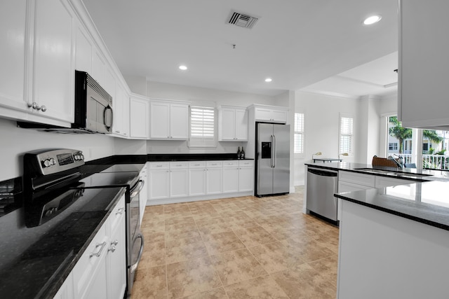 kitchen with appliances with stainless steel finishes, white cabinetry, and a wealth of natural light