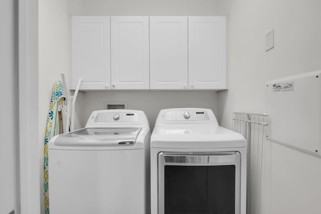 laundry room featuring washing machine and clothes dryer and cabinets