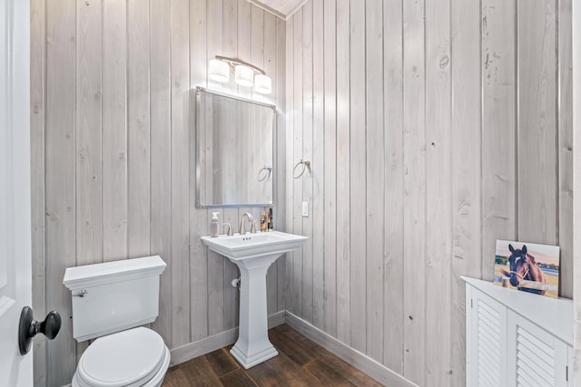 bathroom with hardwood / wood-style floors, wood walls, and toilet