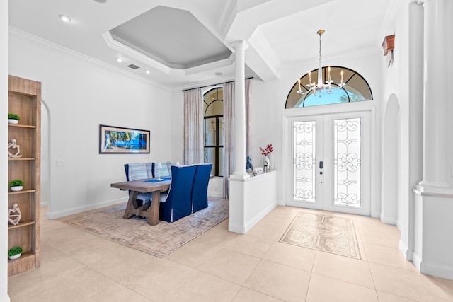 entrance foyer with a chandelier, light tile patterned flooring, ornamental molding, and french doors