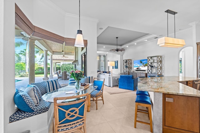 tiled dining area with a tray ceiling, ceiling fan, and ornamental molding