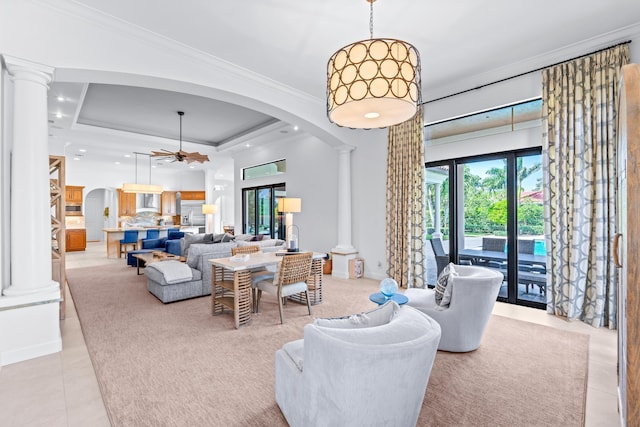 tiled living room featuring ceiling fan, a tray ceiling, and decorative columns