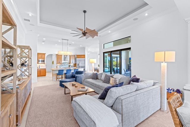 tiled living room featuring a raised ceiling, ceiling fan, and crown molding