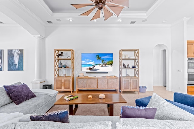 living room featuring decorative columns, crown molding, a tray ceiling, and ceiling fan