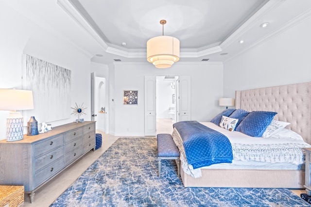 bedroom featuring a raised ceiling, connected bathroom, and crown molding