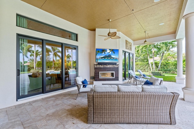 view of patio with an outdoor living space with a fireplace and ceiling fan