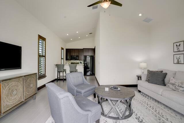 living room featuring ceiling fan, light hardwood / wood-style flooring, and high vaulted ceiling