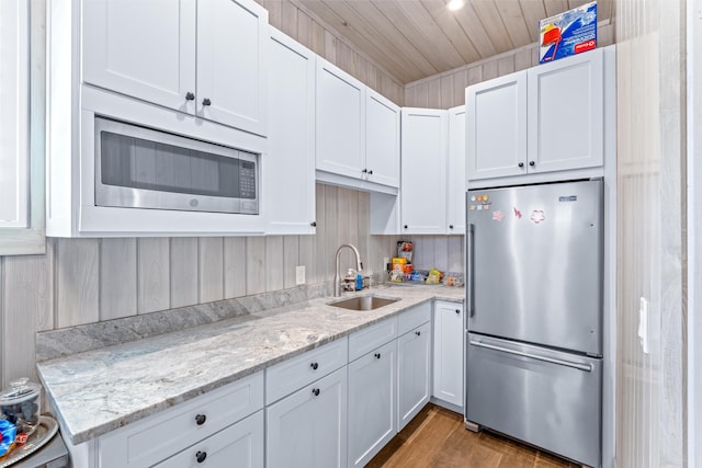 kitchen with hardwood / wood-style floors, appliances with stainless steel finishes, white cabinetry, and sink