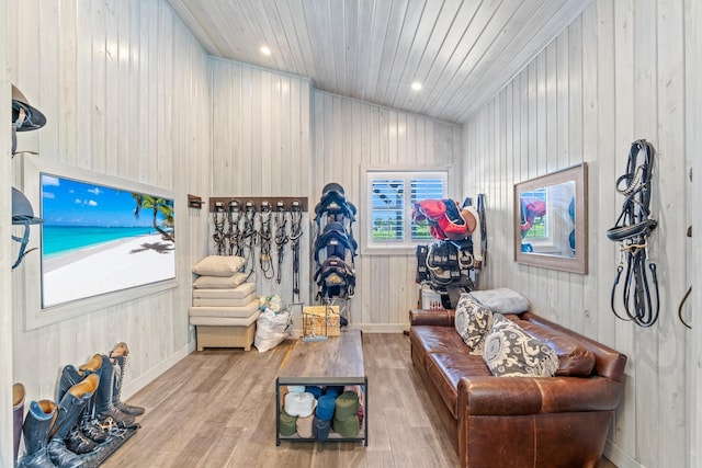 living room featuring wooden walls, light hardwood / wood-style flooring, wood ceiling, and vaulted ceiling