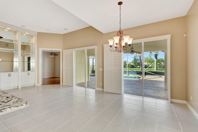 empty room featuring ceiling fan with notable chandelier, baseboards, and light tile patterned floors