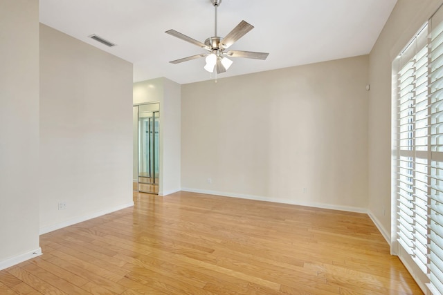 unfurnished room with a ceiling fan, light wood-type flooring, visible vents, and baseboards