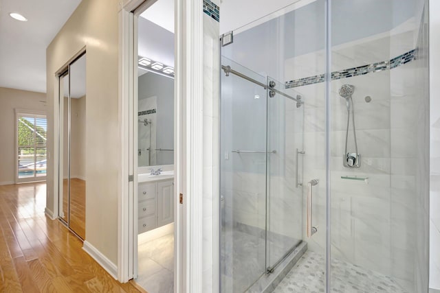 bathroom with a stall shower, baseboards, wood finished floors, and vanity