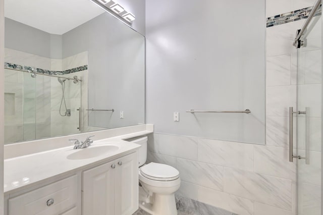 bathroom with tile walls, toilet, a stall shower, wainscoting, and vanity