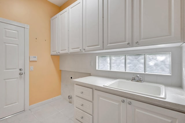 laundry area with cabinet space, baseboards, a sink, electric dryer hookup, and light tile patterned flooring