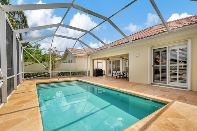 pool featuring ceiling fan, glass enclosure, and a patio