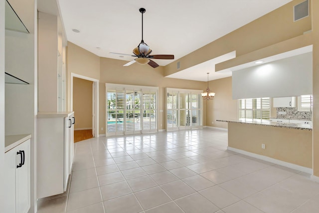 unfurnished room with light tile patterned floors, ceiling fan with notable chandelier, visible vents, and baseboards