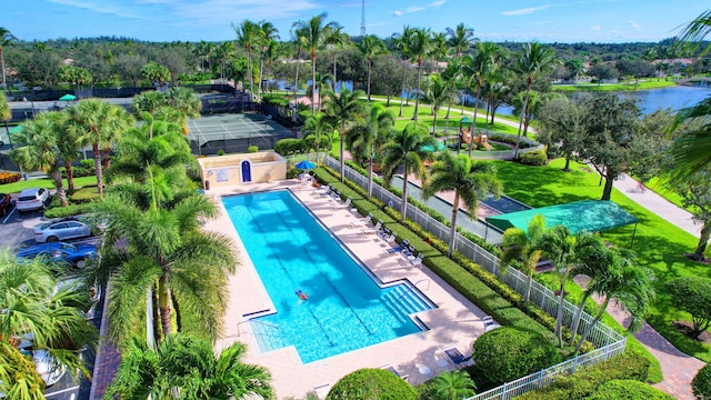 community pool with a patio, a water view, and fence