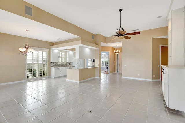 unfurnished living room with ceiling fan with notable chandelier, light tile patterned floors, visible vents, and baseboards