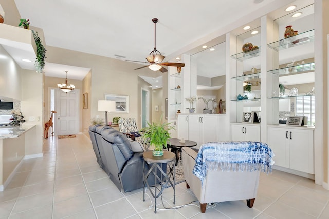 tiled living room with built in shelves and ceiling fan with notable chandelier