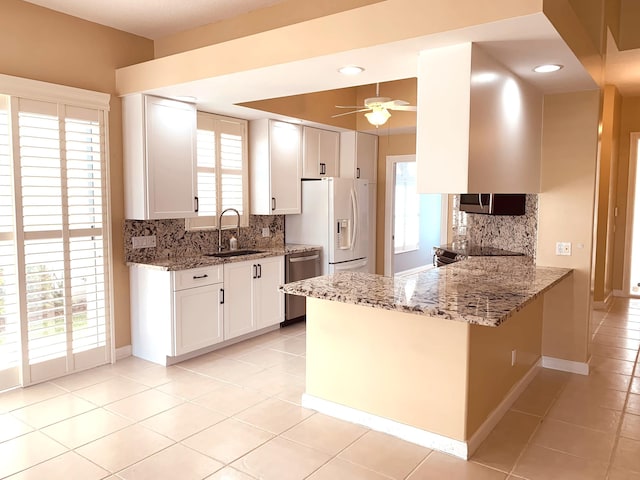 kitchen with white cabinetry, decorative backsplash, kitchen peninsula, and stone countertops