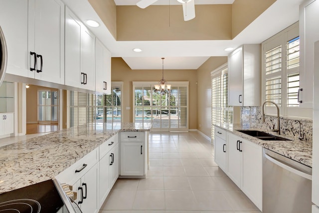 kitchen with light stone counters, pendant lighting, stainless steel dishwasher, white cabinets, and a sink