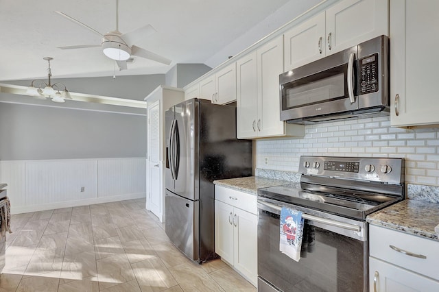 kitchen with light stone countertops, appliances with stainless steel finishes, ceiling fan with notable chandelier, white cabinetry, and lofted ceiling