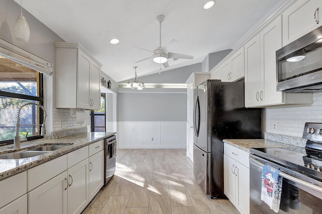 kitchen with light stone countertops, white cabinets, stainless steel appliances, and lofted ceiling