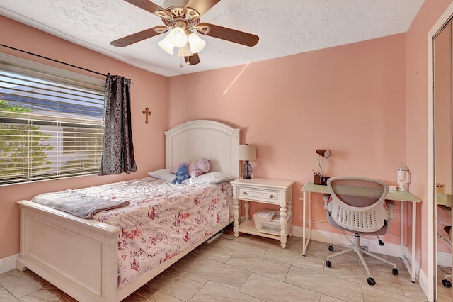 bedroom with ceiling fan, light tile patterned floors, and a textured ceiling