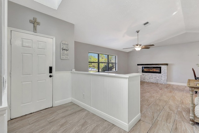 entrance foyer featuring a fireplace, lofted ceiling with skylight, and ceiling fan