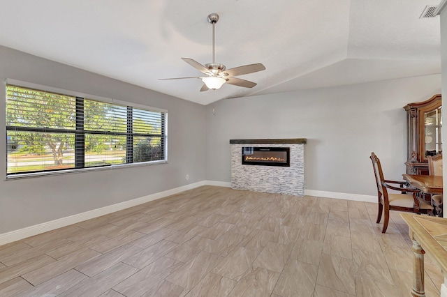 unfurnished living room with a stone fireplace, ceiling fan, and lofted ceiling