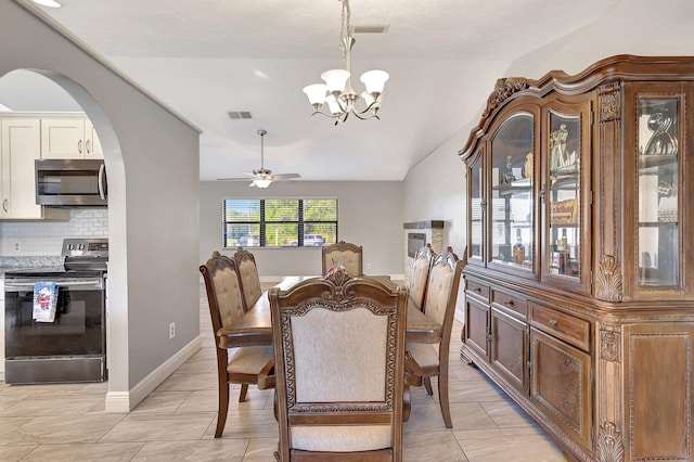 tiled dining room featuring ceiling fan with notable chandelier and vaulted ceiling