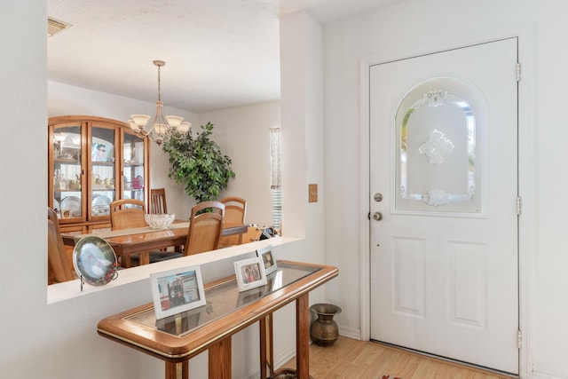 foyer entrance featuring a chandelier and light hardwood / wood-style flooring