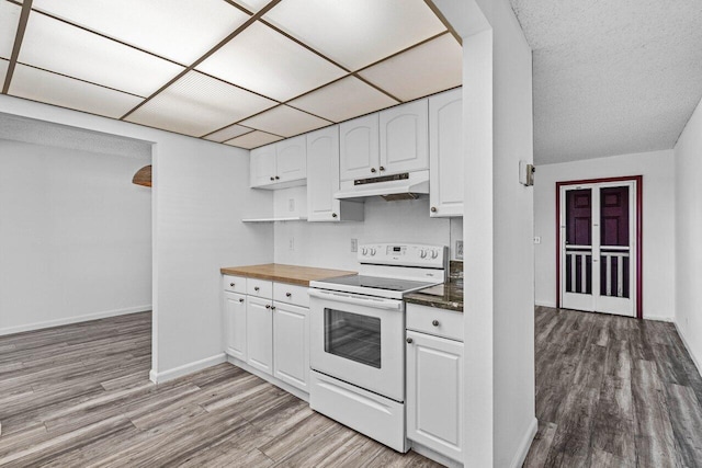 kitchen with a drop ceiling, electric range, light wood-type flooring, white cabinetry, and butcher block counters