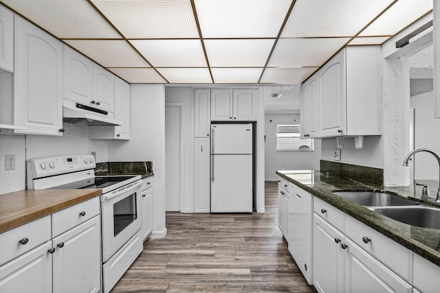 kitchen featuring sink, white cabinets, dark stone counters, and white appliances