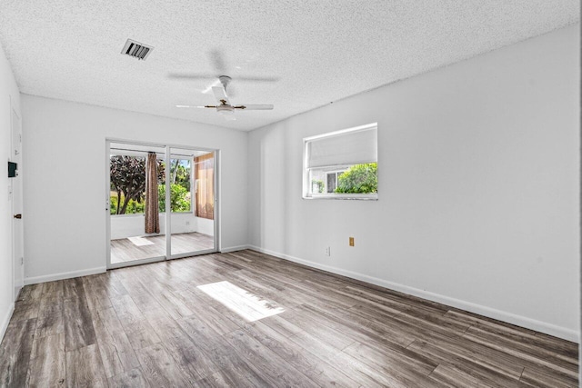 empty room featuring hardwood / wood-style flooring, a healthy amount of sunlight, and a textured ceiling