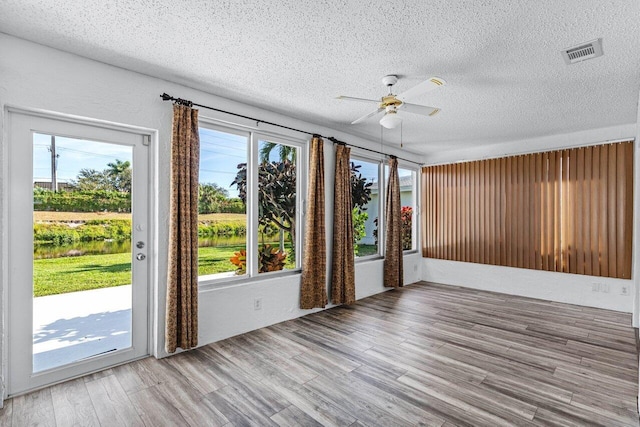 unfurnished room with hardwood / wood-style floors, a textured ceiling, plenty of natural light, and ceiling fan