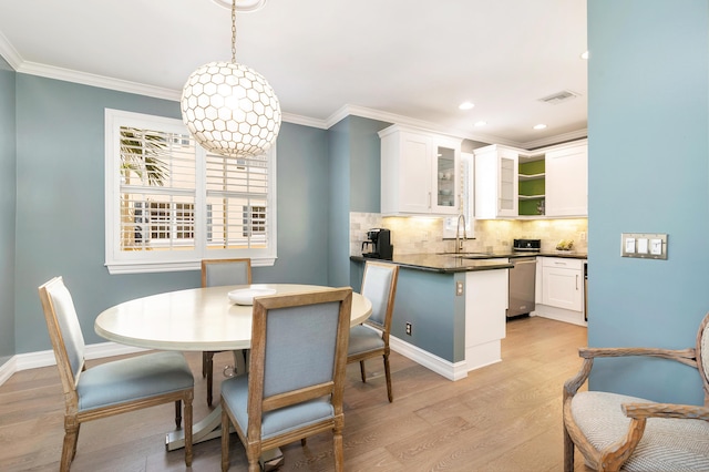 dining room with crown molding, light wood-type flooring, and sink