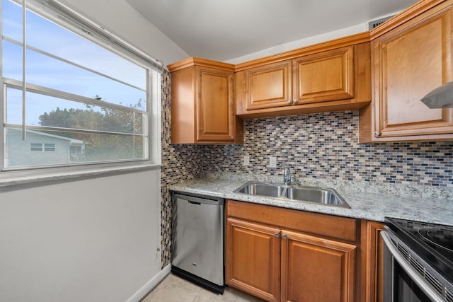 kitchen with stainless steel dishwasher, light stone countertops, sink, and tasteful backsplash