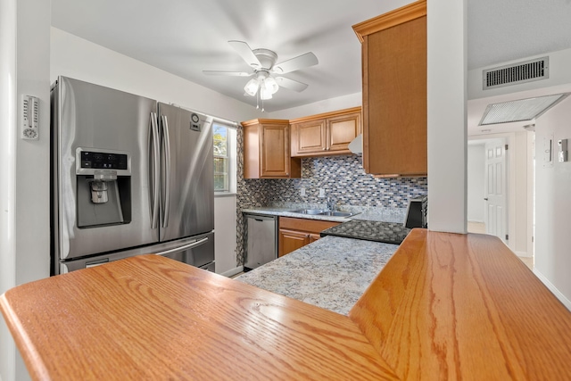 kitchen with kitchen peninsula, appliances with stainless steel finishes, backsplash, ceiling fan, and sink