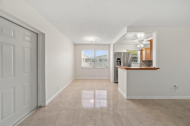 interior space with ceiling fan, light tile patterned flooring, and a textured ceiling