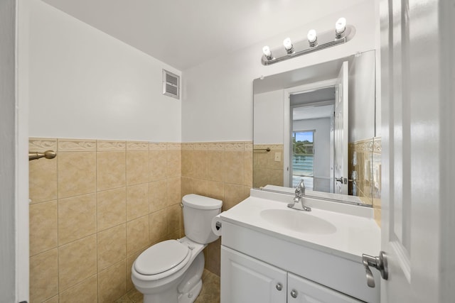 bathroom featuring vanity, toilet, and tile walls