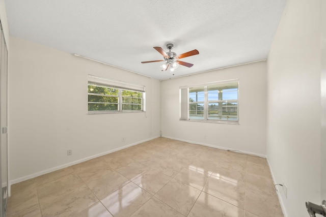 unfurnished room with ceiling fan, light tile patterned floors, and a textured ceiling