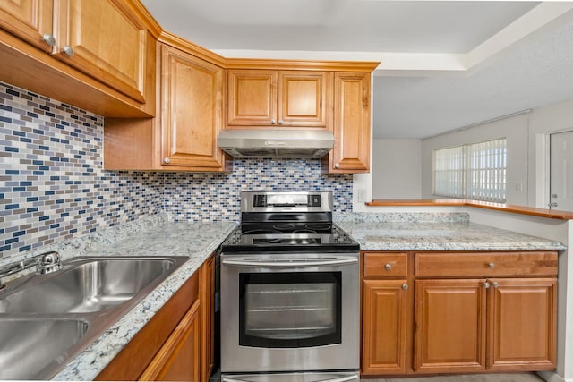 kitchen with backsplash, light stone counters, sink, and stainless steel range with electric stovetop