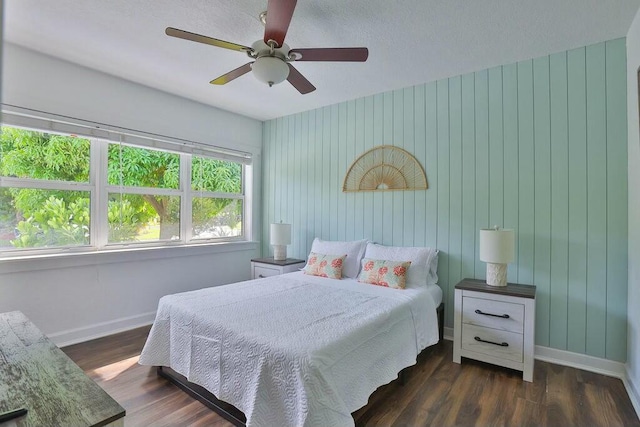 bedroom featuring ceiling fan, wood walls, and dark hardwood / wood-style floors