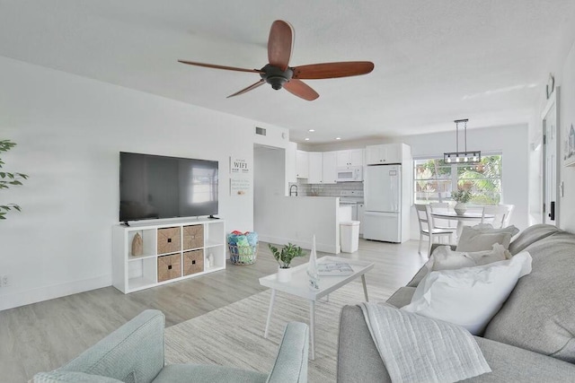 living room with ceiling fan and light hardwood / wood-style flooring