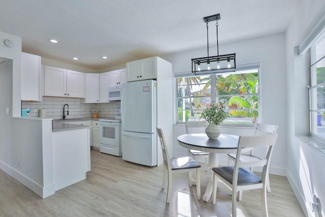 kitchen with white cabinets, a healthy amount of sunlight, white appliances, and hanging light fixtures